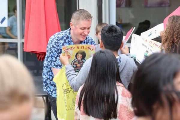 十大正规博彩网站评级博彩平台推荐大学 Children's Literature Conference speaker John Schu signs books for schoolchildren at a Rally for 阅读 to kick off the virtual/in-person conference in April.